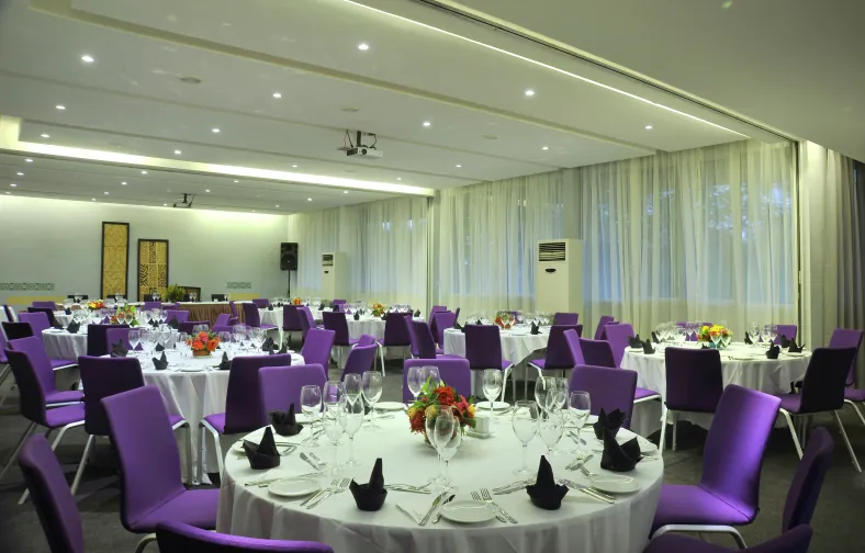 Salle de banquet dressée, nappes blanches et chaises violettes